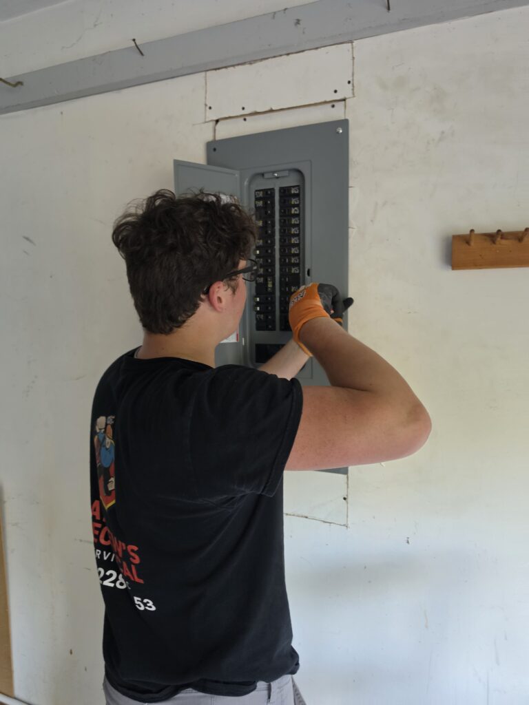 Electrician reaching into an open breaker box during a panel upgrade