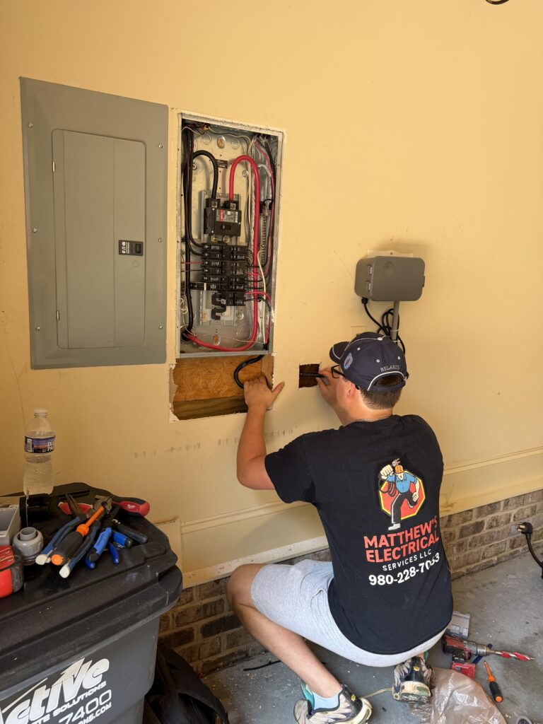 Electrician kneeling beside an open garage panel during an upgrade