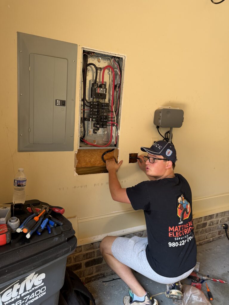 Electrician patching the wall beside a garage electrical panel