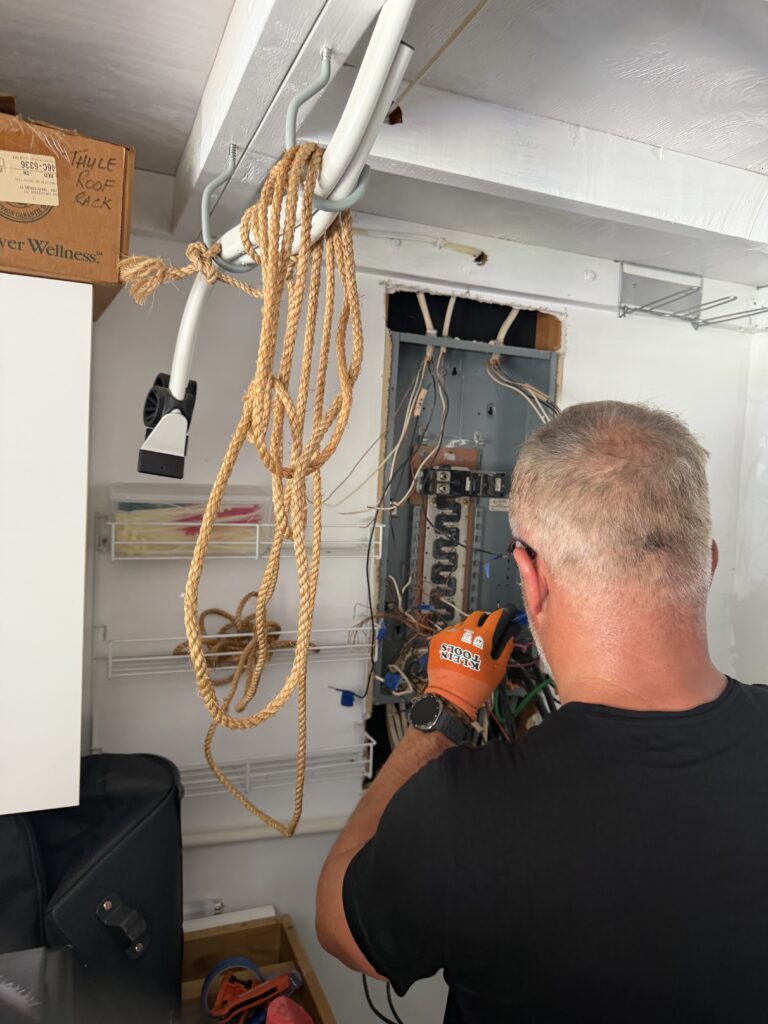Electrician working on an older electrical panel with loose wiring
