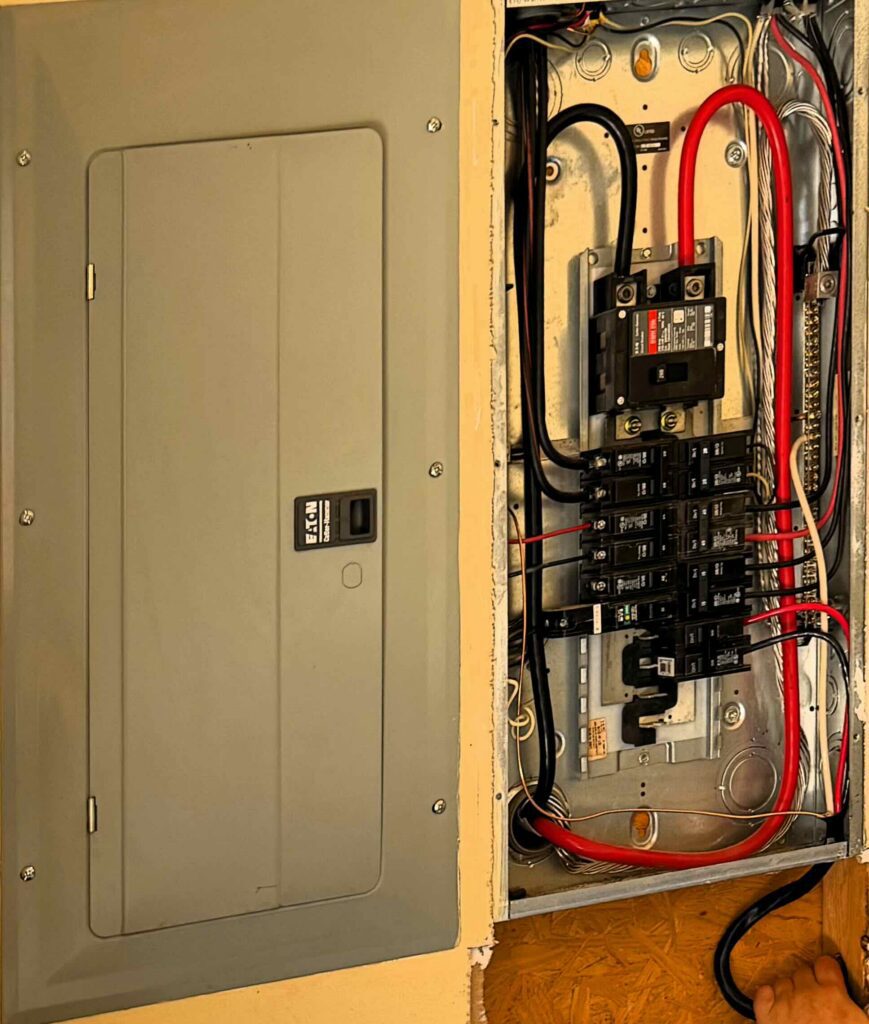 Newly wired breaker panel with its cover open and cables on the breakers