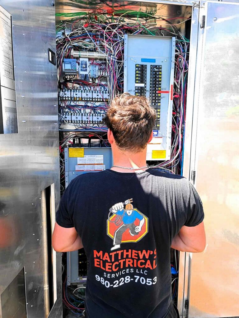 Electrician inspecting an outdoor electrical cabinet and panel wiring