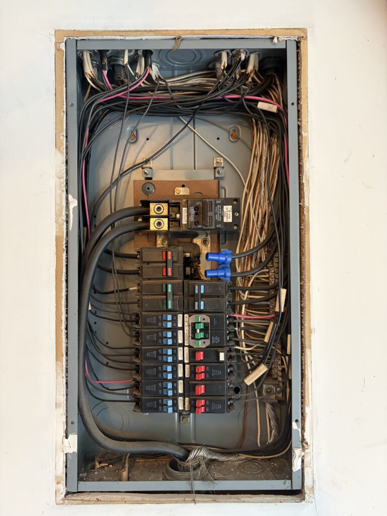Close-up of a breaker panel with neatly routed cables above the main